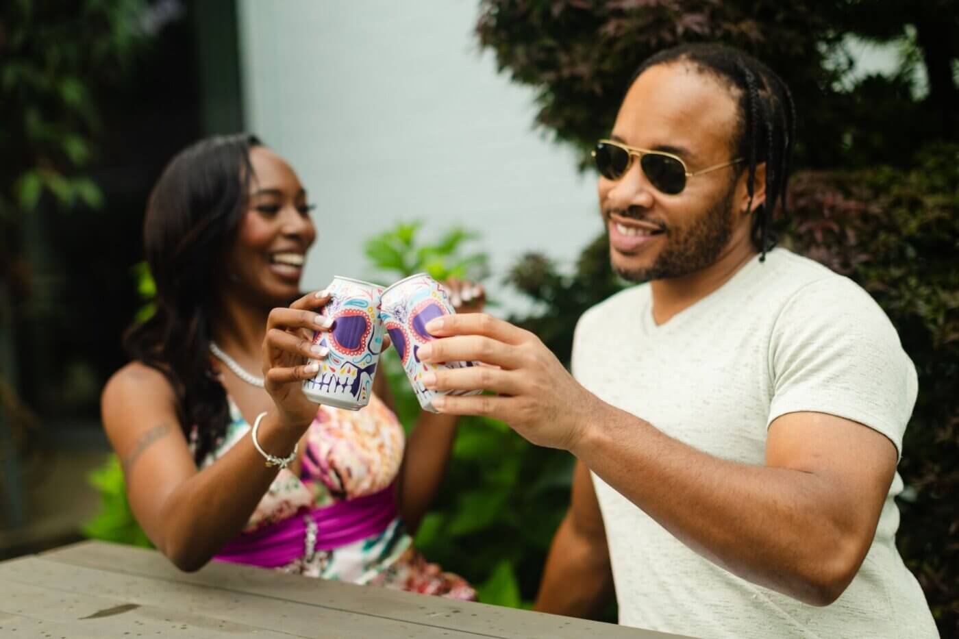 Man and woman doing cheers with their cans of Stone Buenaveza