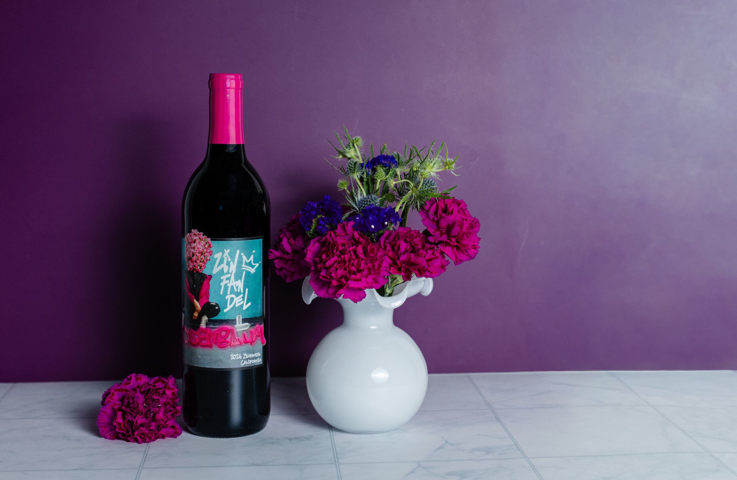 Bottle of Rosenblum Vintner's Cuvée Zinfandel next to white vase full of bright colored flowers