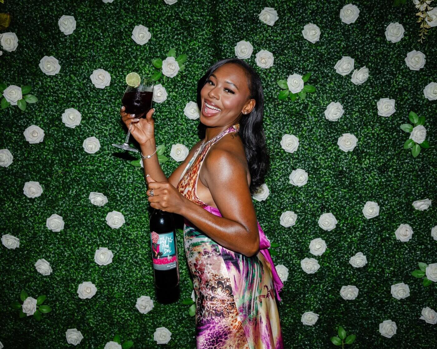 Woman smiling holding bottle of Rosenblum Vintner's Cuvée Zinfandel with glass filled up