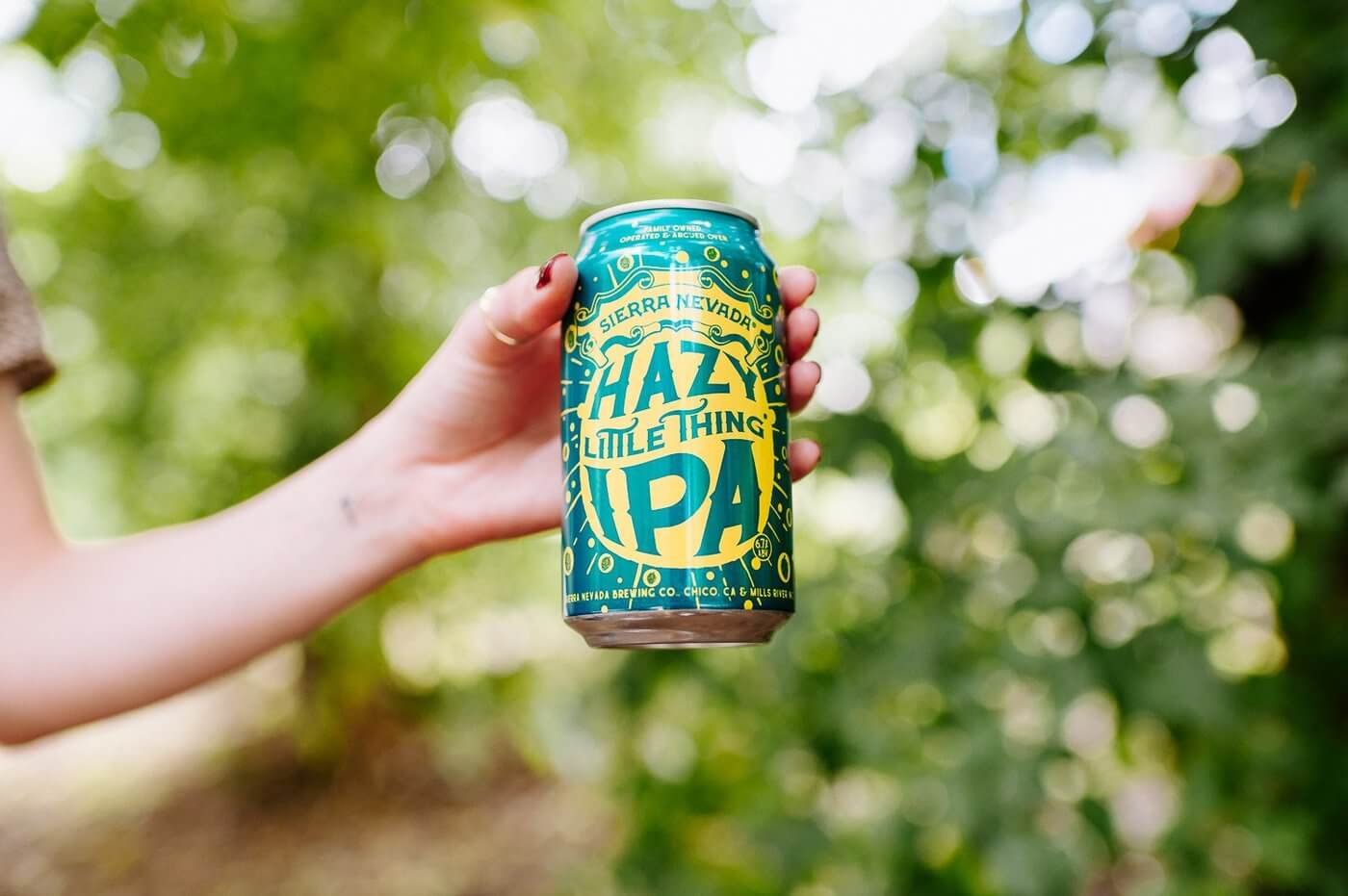 Hand holding out can of Sierra Nevada Hazy Little Thing IPA beer can